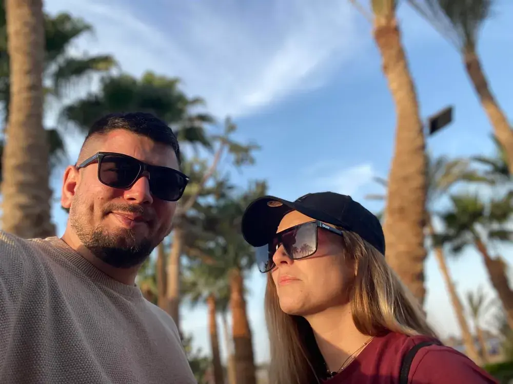 Selfie of Viktoria and Roland in sunglasses under palm trees